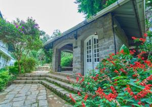 a stone house with a door and some flowers at Ministers Mansion Kanthalloor Pool Resort by VOYE HOMES in Kanthalloor
