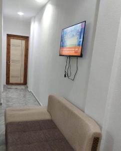 a flat screen tv hanging on a wall with a couch at Appartement S1 Tulipe in Zarzis