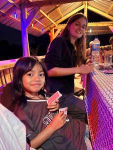 a young girl sitting next to a woman holding a cell phone at Bareng Homestay Tetebatu in Tetebatu