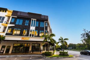 a building on the corner of a street with palm trees at Mood Hotel in Skudai