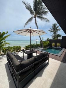 a patio with a couch and an umbrella and a pool at Villa Miario in Koh Samui