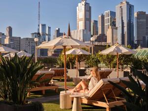 a woman sitting in a chair under umbrellas in a city at The Langham Melbourne in Melbourne