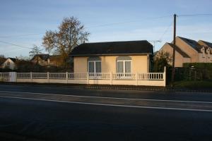 a house with a white fence on the side of a road at La Doris in Saint-Pair-sur-Mer