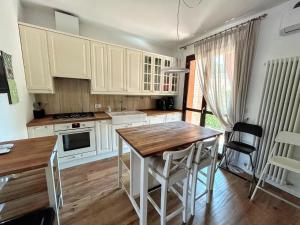 a kitchen with white cabinets and a wooden table at Nice villa with pool and garden in Fermignano