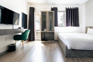a bedroom with a bed and a green chair at Nicecy Hotel - 218 Le Thanh Ton Street in Ho Chi Minh City