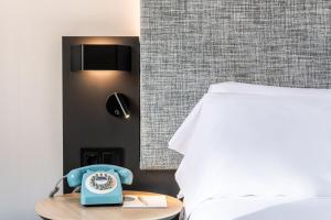 a blue alarm clock sitting on a table next to a bed at INNSiDE by Meliá Valencia Oceanic in Valencia