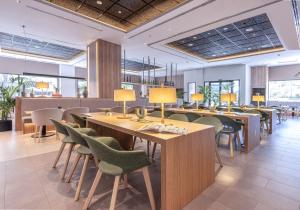 a restaurant with wooden tables and green chairs at INNSiDE by Meliá Valencia Oceanic in Valencia