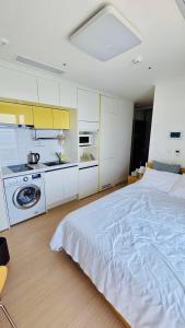 a white bedroom with a large bed and a kitchen at 양양 죽도해변호텔 오션뷰스테이 일출뷰 바다뷰 힐링뷰 낭만뷰 넷플릭스완 in Saetchak