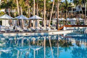 a pool with chairs and umbrellas and palm trees at Paradisus by Meliá Los Cabos - Adults Only - All Inclusive in San José del Cabo