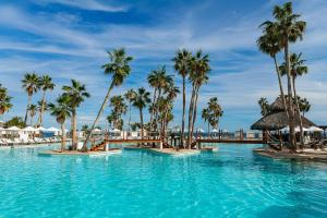 a swimming pool with palm trees and a bridge at Paradisus by Meliá Los Cabos - Adults Only - All Inclusive in San José del Cabo