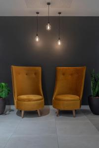 two orange chairs sitting in a room with plants at INNSiDE by Meliá Newcastle in Newcastle upon Tyne