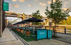 a row of tables and chairs with a bridge in the background at INNSiDE by Meliá Newcastle in Newcastle upon Tyne +92 photos