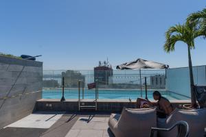 a person sitting in chairs next to a swimming pool at Skylux by Tegra in Rio de Janeiro