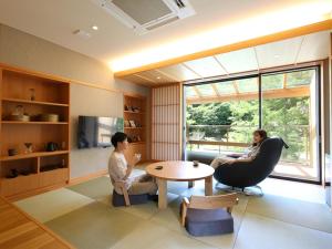 two people sitting in a living room with a table at Keiryuso Siorie in Matsumoto