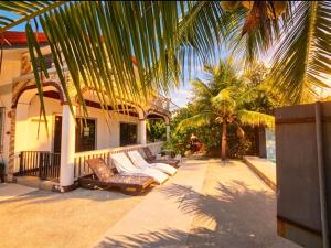 a porch of a house with couches and palm trees at FFG Eden Private Resort in Basdiot