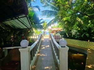 a wooden walkway leading to a beach with palm trees at FFG Eden Private Resort in Basdiot +67 photos
