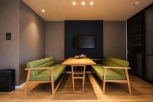 a room with two green chairs and a table and a tv at 5 minutes Shin-Osaka 9 in Osaka