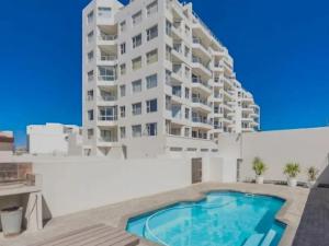 a building with a swimming pool in front of a building at Cape Town Beachfront Accommodation in Blouberg in Bloubergstrand