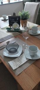 a wooden table with plates and bowls and a wine glass at Gute Stube - Ferienhaus NaheZeit Bostalsee in Nohfelden