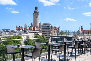 a balcony with tables and chairs and a view of a city at INNSiDE by Meliá Leipzig in Leipzig