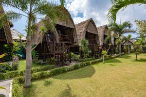a row of cottages with palm trees and grass at Dream Beach Kubu & SPA by ABM in Nusa Lembongan