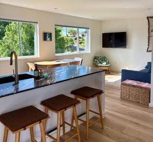 a kitchen and living room with a counter and stools at The Four Cedars in Ucluelet