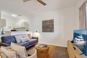 ein Wohnzimmer mit einer blauen Couch und einem Fernseher in der Unterkunft Shell Escape in Broome