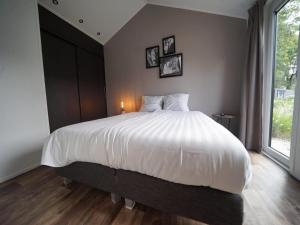 a bedroom with a large white bed with a window at Nature Chalet Near Efteling in Kaatsheuvel +15 photos