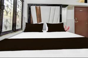 a bedroom with a large white bed with black pillows at Hotel Birhana road in Kānpur