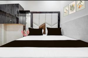 a bedroom with a large white bed with black pillows at Hotel Birhana road in Kānpur