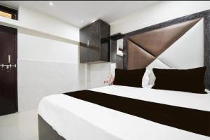a bedroom with a large white bed with black pillows at Hotel Birhana road in Kānpur