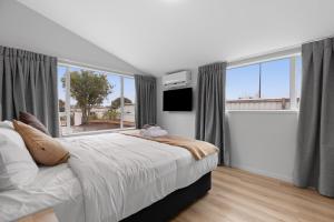 a bedroom with a large bed and a large window at Brookside Residence in Rolleston