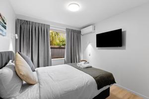 a bedroom with a bed and a television on the wall at Brookside Residence in Rolleston
