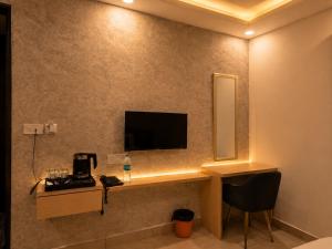a hotel room with a desk with a television on the wall at Hotel Smart Snap Sector 104, Noida in Noida