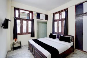 a bedroom with a large bed in a room with windows at Hotel O Patel Nagar Patna Formerly Princess Home in Patna
