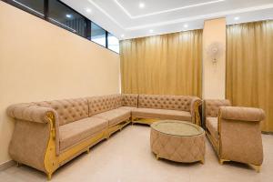 a large couch and two chairs in a room at Townhouse Defence Colony Noida in Greater Noida