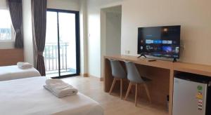 a room with a bed and a desk with a flat screen tv at Ceniq Hotel in Sathani Nakhon Lampang