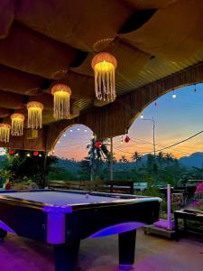 a pool table in front of a building with chandeliers at Woodstock Beach Camp in Cat Ba