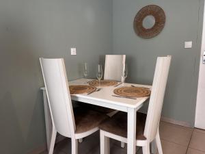 a white table with two chairs and a white table with wine glasses at L'appart de juju in Petite Île