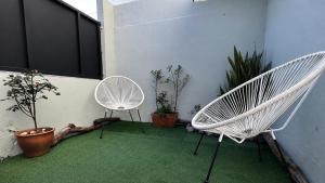two white chairs sitting on a patio with plants at L'appart de juju in Petite Île