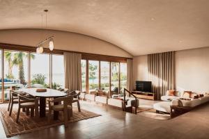 a living room with a table and chairs and a television at Miraval The Red Sea All Inclusive Adults Only in Ḩanak