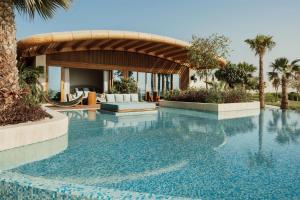 a swimming pool in a resort with palm trees at Miraval The Red Sea All Inclusive Adults Only in Ḩanak