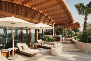 a patio with chairs and umbrellas on a building at Miraval The Red Sea All Inclusive Adults Only in Ḩanak