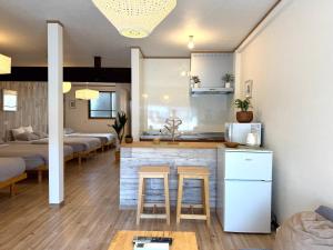 a living room with two beds and a kitchen with stools at 金森赤レンガ倉庫徒歩すぐ 伝統建築リノベ貸切 最大8名 最新設備 in Hakodate