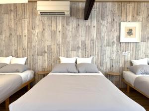 two beds in a room with wooden walls at 金森赤レンガ倉庫徒歩すぐ 伝統建築リノベ貸切 最大8名 最新設備 in Hakodate