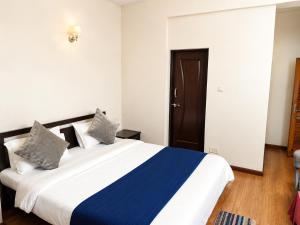a bedroom with a large bed with blue and white sheets at Hotel Maurya Regency in Morjim