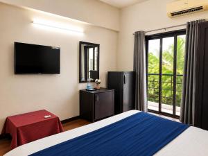 a bedroom with a bed and a flat screen tv at Hotel Maurya Regency in Morjim