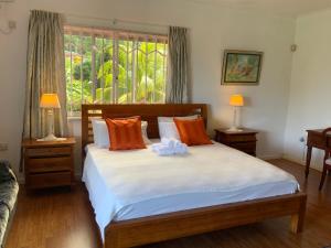 a bedroom with a bed with orange and white pillows at The Orchard Holiday Home in Mahe +136 photos