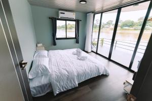 a bedroom with a bed and a large window at แพ River Tale Uthaithani in Ban Khok Mo