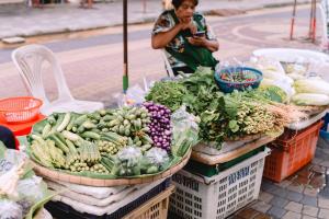 a man standing in front of a market with vegetables at แพ River Tale Uthaithani in Ban Khok Mo